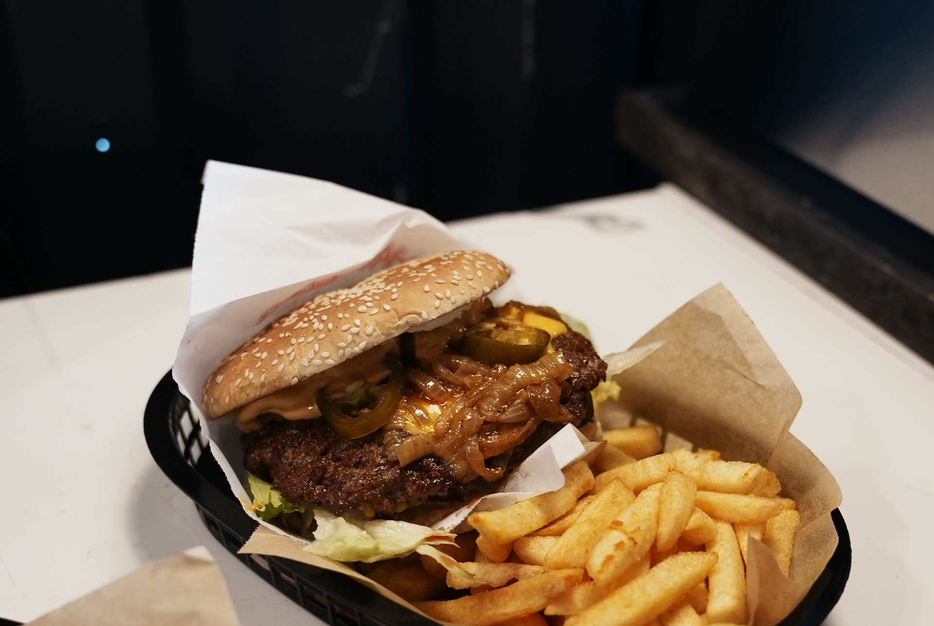 Smash-Cheeseburger mit Jalapeños und Pommes im Korb