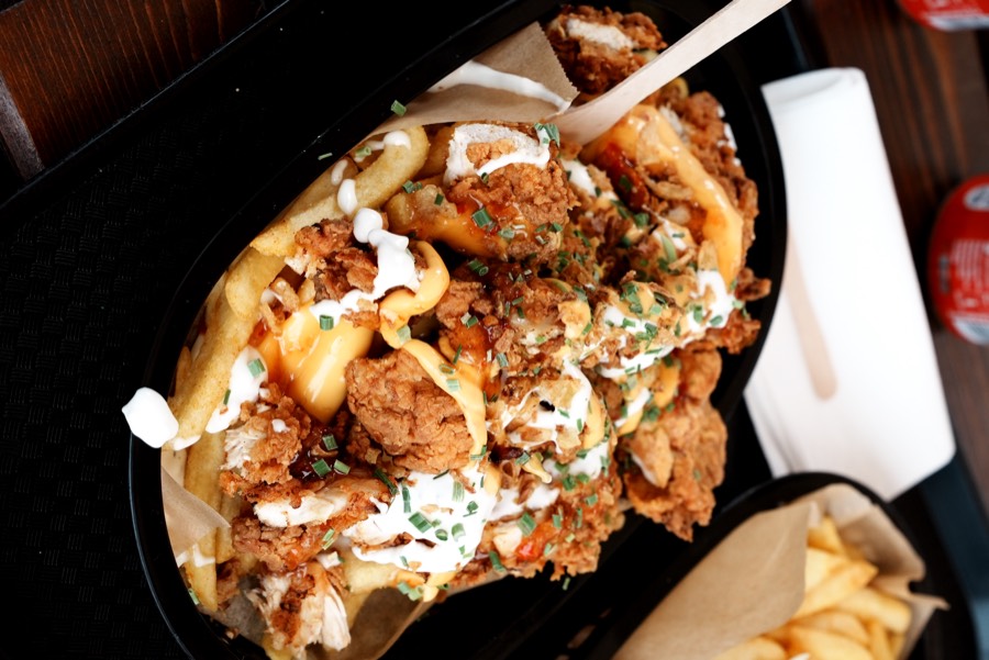 Loaded Fries mit Fried Chicken auf schwarzem Tablett